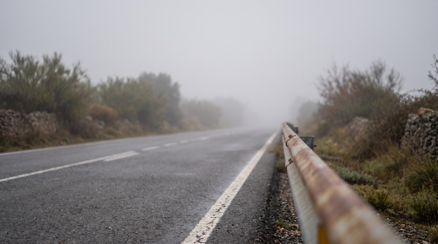 Carretera española desapareciendo entre niebla densa con muy poca visibilidad
